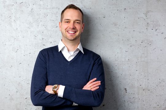 Fabian lehnt lächelnd an Wand